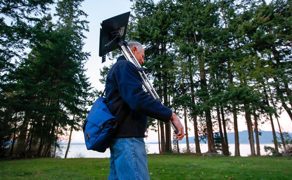 A person carrying a portable easel with a Maker's Bag slung cross-body.